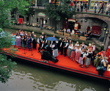 840368 Afbeelding van een zangkoor dat zingt op een 'muziekboot' op de Oudegracht bij de Bezembrug te Utrecht, tijdens ...
